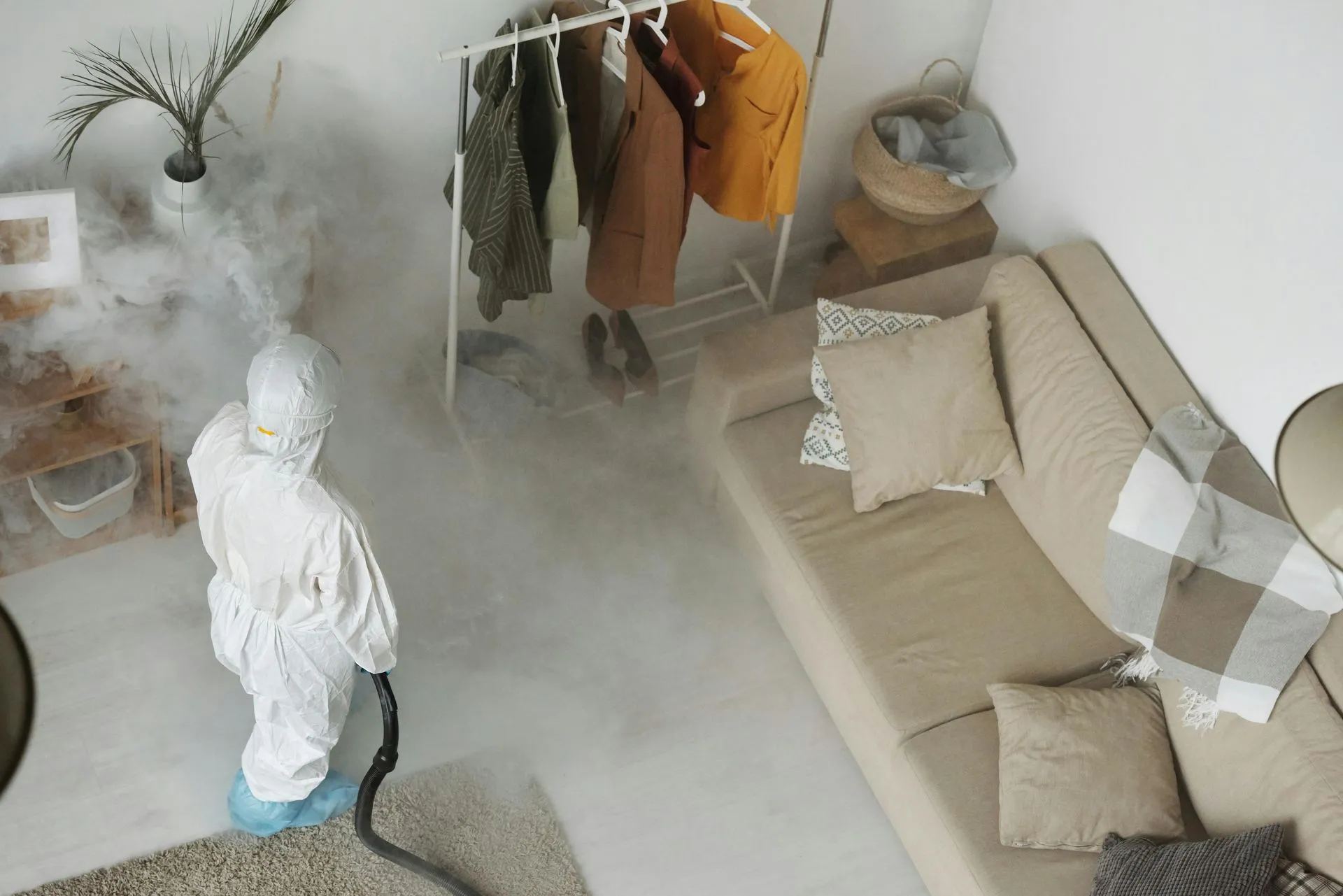 House A person in a protective suit is cleaning a living room with a vacuum cleaner.